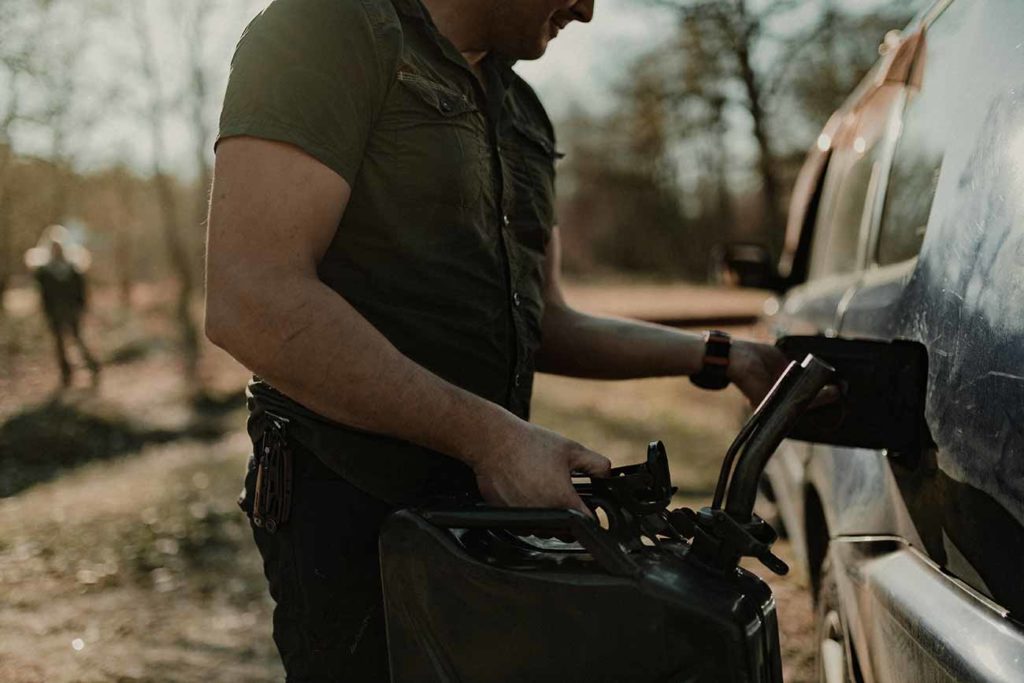 Un homme fait le plein avec un jerrican.