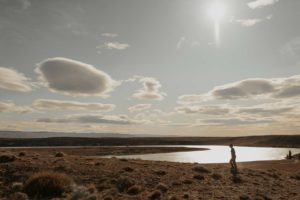 Femme qui marche au bord d'un lac ensoleillé en plein désert.
