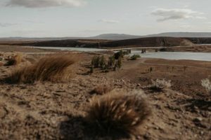 Paysage aride et pont qui passe haut dessus d'une rivière.