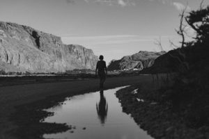 Femme qui marche au milieu des montagnes en noir et blanc.