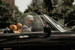 Le marié s'apprête à partir en voiture décapotable.