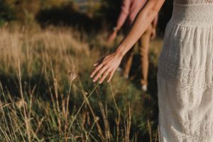 Main d'une femme qui touche les hautes herbes.