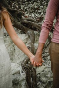 Racine d'arbre derrière les mains d'un couple.