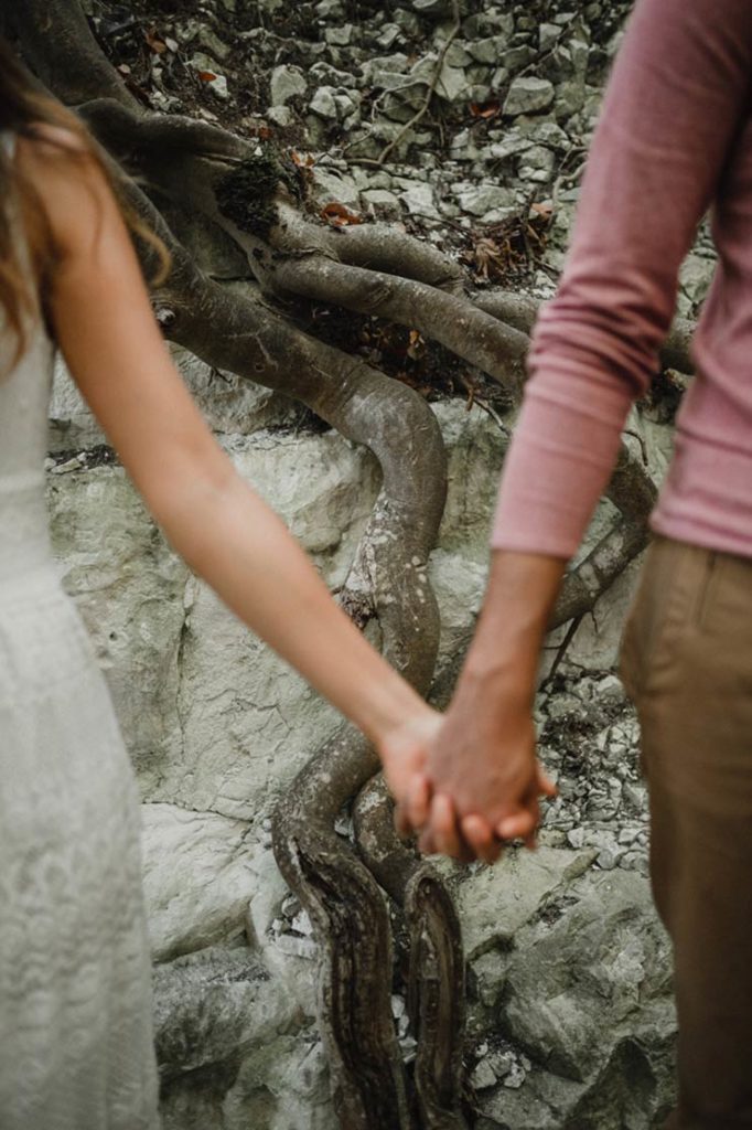 Racine d'arbre derrière les mains d'un couple.