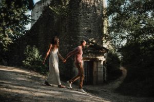 Couple qui marche devant une tour médiévale.