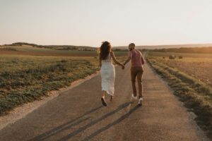 Un couple coure sur route au milieu des champs.