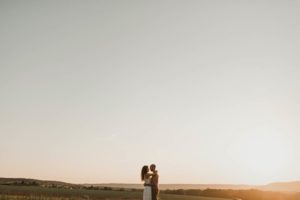 Un couple enlacé au milieu de la campagne.