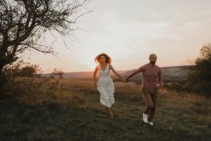 Couple qui coure main dans la main au soleil couchant.