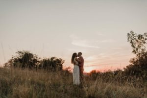 Couple qui s'embrasse au coucher de soleil dans les hautes herbes.