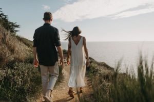 Couple qui se promène sur un sentier en bord de mer.