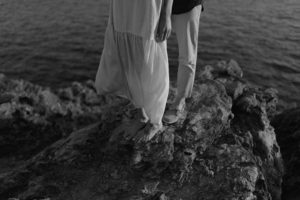 Jambes d'un couple sur les rochers en bord de mer.