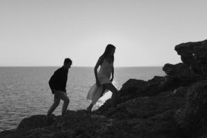 Couple qui marche dans les rochers en bord de mer.